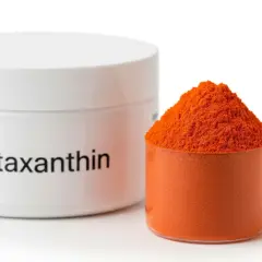 Słoiczek z napisem "Astaxanthin" obok miarki wypełnionej pomarańczowym proszkiem. Ten silny antyoksydant, astaksantyna, jest gotowy do użycia.