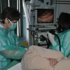 Przygotowanie do gastroskopii: lekarze w fartuchach i maskach obserwują obraz z endoskopu na monitorze.