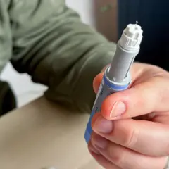 Dłoń trzymająca wstrzykiwacz z igłą. Osoba przygotowuje się do podania leku, być może zastanawiając się nad potencjalnymi mounjaro skutki uboczne.