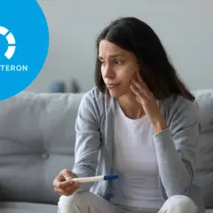 Zmartwiona kobieta trzyma test ciążowy. Ikona z napisem "PROGESTERON" sugeruje, że może to być związane z niskim progesteronem objawy.