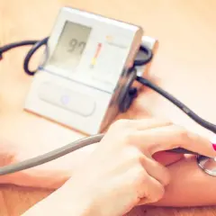 Dwie osoby mierzą ciśnienie. Jedna ręka trzyma pompkę, druga stetoskop. Na ekranie ciśnieniomierza widnieje wynik 97. To ważny pomiar dla zdrowia, jak ten z hygrotonem.