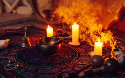 Obrzędowa atmosfera z palącymi się świecami, misą, dzwonkiem i marakasami, sugerująca ceremonię z użyciem ayahuasca.