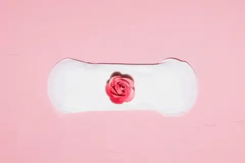 Delikatne plamienie implantacyjne, symbolizujące początek nowego życia, przedstawione na różowym tle z różą.