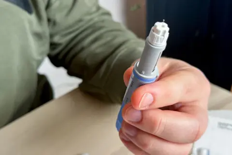 Dłoń trzymająca wstrzykiwacz z igłą. Osoba przygotowuje się do podania leku, być może zastanawiając się nad potencjalnymi mounjaro skutki uboczne.