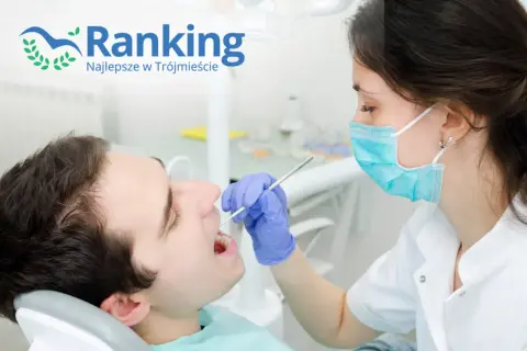Dentystka w masce bada zęby pacjenta narzędziem stomatologicznym.