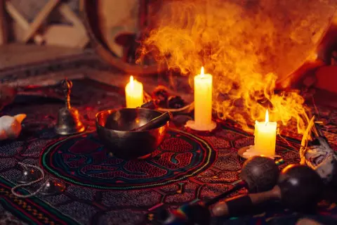 Obrzędowa atmosfera z palącymi się świecami, misą, dzwonkiem i marakasami, sugerująca ceremonię z użyciem ayahuasca.