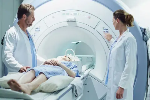 Pacjentka leży w aparacie do rezonansu magnetycznego, gdzie lekarze przygotowują badanie z kontrastem.