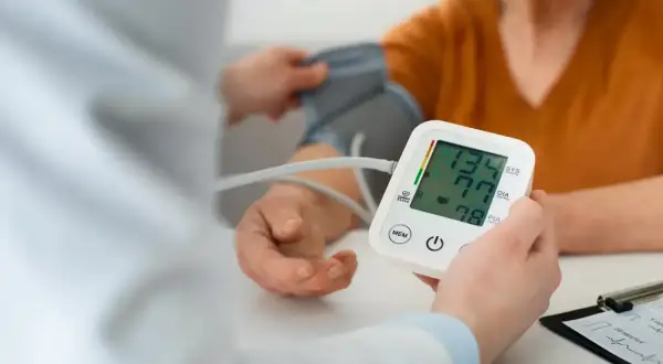 Lekarz mierzy ciśnienie pacjentowi, monitorując potencjalne objawy nadciśnienia. Wynik 134/77 mmHg.