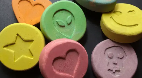 Kolorowe tabletki z symbolami: serce, uśmiech, czaszka, gwiazda, kosmita. To mogą być tabletki MDMA.