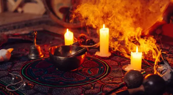 Obrzędowa atmosfera z palącymi się świecami, misą, dzwonkiem i marakasami, sugerująca ceremonię z użyciem ayahuasca.