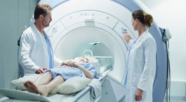 Pacjentka leży w aparacie do rezonansu magnetycznego, gdzie lekarze przygotowują badanie z kontrastem.