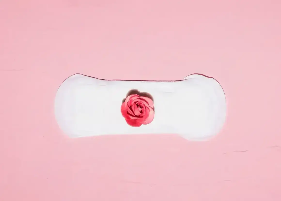 Delikatne plamienie implantacyjne, symbolizujące początek nowego życia, przedstawione na różowym tle z różą.