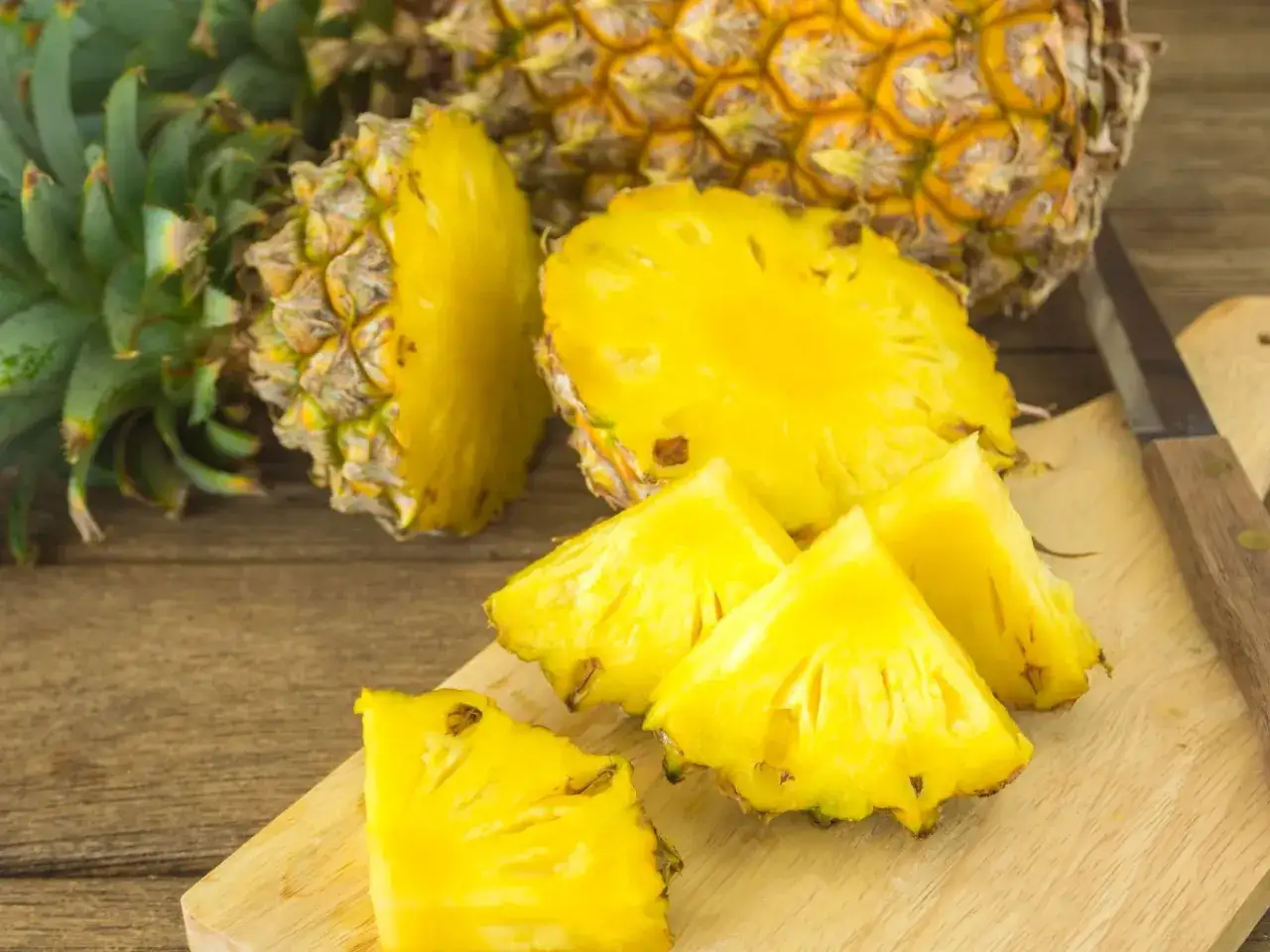 Pokrojony ananas na desce, ukazujący jego soczyste wnętrze. Poznaj ananas właściwości i ciesz się jego smakiem.