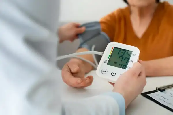 Lekarz mierzy ciśnienie pacjentowi, monitorując potencjalne objawy nadciśnienia. Wynik 134/77 mmHg.