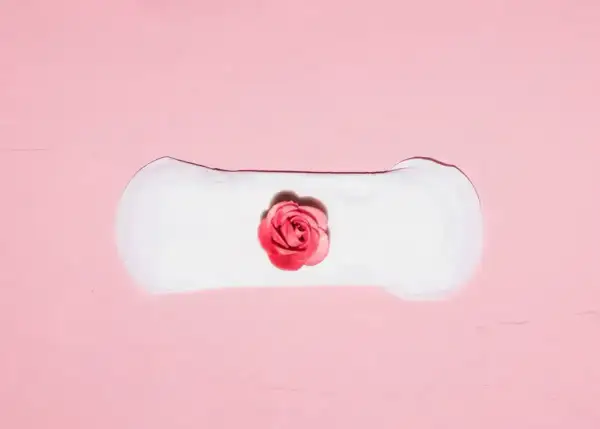 Delikatne plamienie implantacyjne, symbolizujące początek nowego życia, przedstawione na różowym tle z różą.